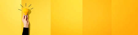Person holding a yellow light bulbの写真素材