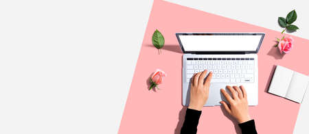 Woman using her laptop with pink rosesの写真素材