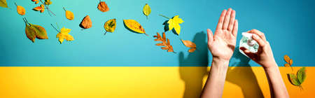 Applying sanitizer gel with autumn leaves