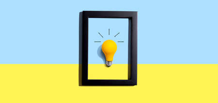 Yellow light bulb inside a frame - inspiration, creativity themesの写真素材