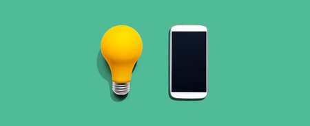 Smartphone with a yellow light bulbの写真素材