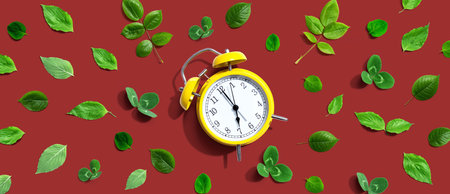 Yellow vintage alarm clock with green leaves