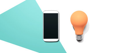Smartphone with a yellow light bulbの写真素材
