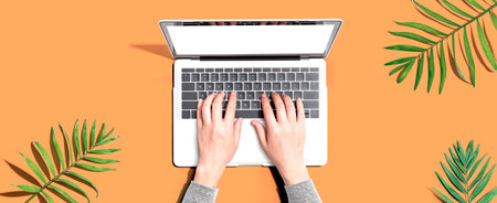Person using a laptop computer with tropical leavesの写真素材