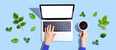 Person using a laptop computer with green leavesの写真素材