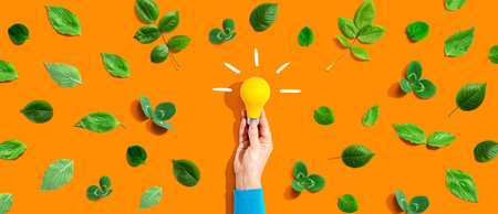 Person holding a lightbulb with green leavesの写真素材