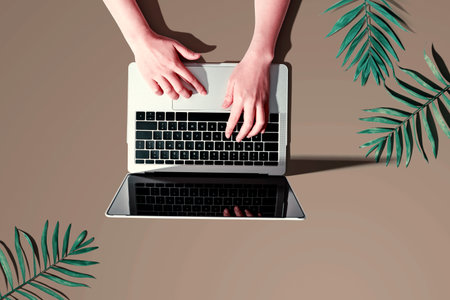 Person using a laptop computer with tropical leavesの写真素材