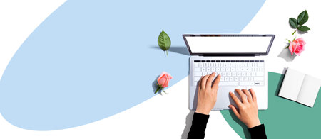 Woman using her laptop with pink rosesの写真素材