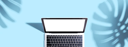 Laptop computer with shadow of tropical leavesの写真素材