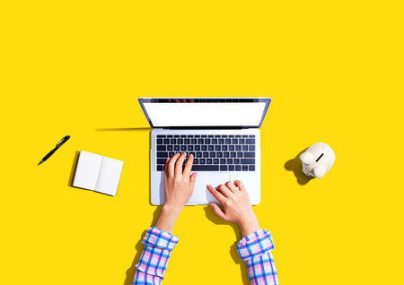 Woman using a laptop computer with a piggy bankの写真素材