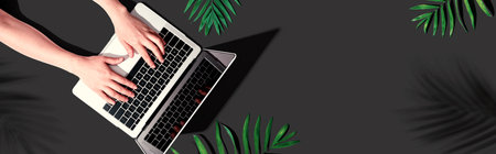 Person using a laptop computer with tropical leavesの写真素材