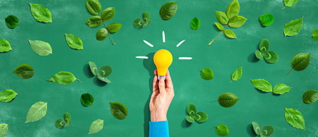 Person holding a lightbulb with green leavesの写真素材