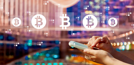 Bitcoin theme with person using a smartphone in city at nightの写真素材