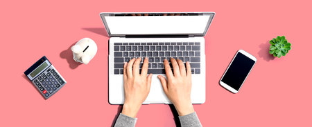 Woman using a laptop computer with a piggy bankの写真素材