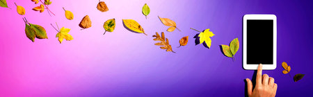 Autumn leaves with person using a tablet computerの写真素材