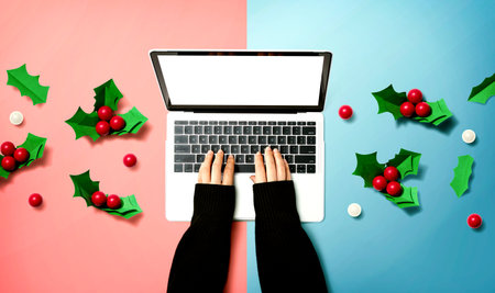 Person using a laptop computer with Christmas holly berriesの写真素材