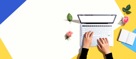 Woman using her laptop with pink rosesの写真素材