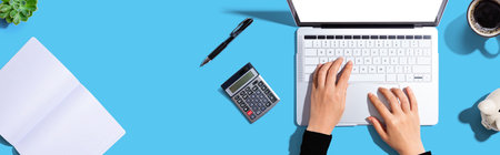 Woman using a laptop computer with a calculatorの写真素材
