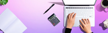 Woman using a laptop computer with a calculatorの写真素材