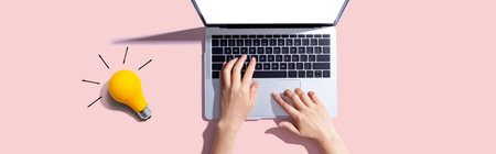 Person using a laptop computer and a light bulbの写真素材