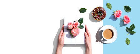 Female hands holding a gift box with pink rosesの写真素材
