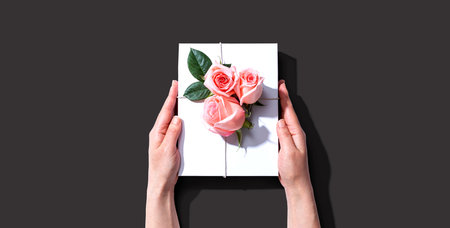 Female hands holding a gift box with pink rosesの写真素材