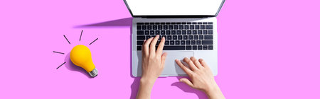Person using a laptop computer and a light bulbの写真素材