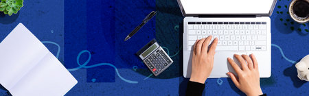 Woman using a laptop computer with a calculatorの写真素材