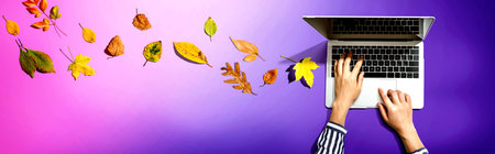 Autumn leaves with person using a laptop computerの写真素材