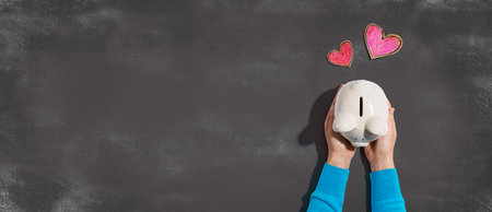 Person holding piggy bank with heartsの写真素材