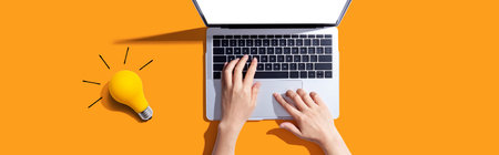 Person using a laptop computer and a light bulbの写真素材