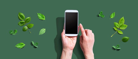 Person using a smartphone with green leavesの写真素材