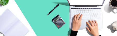 Woman using a laptop computer with a calculatorの写真素材