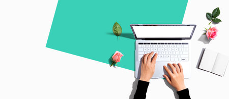 Woman using her laptop with pink rosesの写真素材