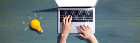 Person using a laptop computer and a light bulbの写真素材