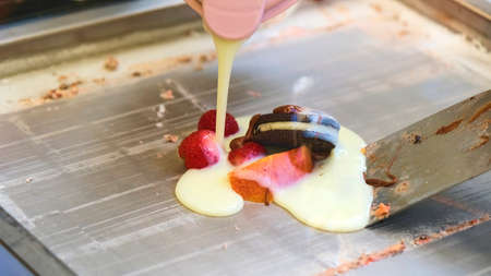 Pouring condensed milk on a chocolate pancake with fresh berries.の写真素材