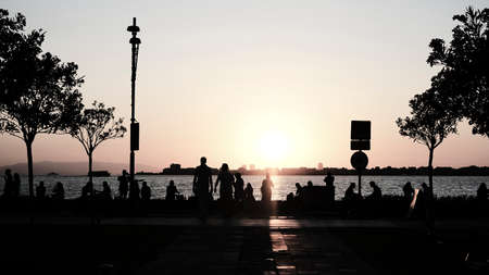 Silhouette of people on the embankment at sunset.の写真素材