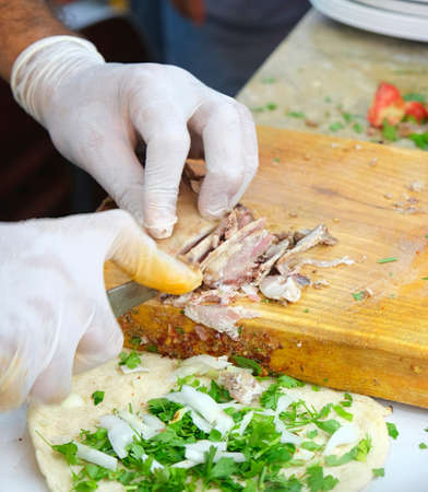 Chef hands in gloves cutting meat with a knife on a wooden boardの写真素材