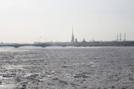 Ice floes float along the wide, deep river Neva. View from the embankment of St. Petersburg to the city panorama. In the distance you can see a bridge, an old ship and a fortress.の写真素材
