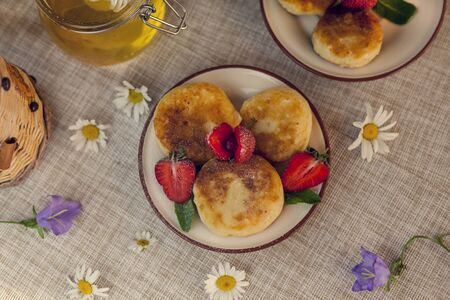 Cottage cheese pancakes, curd fritters with fresh berries strawberries with daisy flowersの写真素材