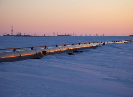 Gas pipelines, crane and pipes for gas and oil transportation, gas processing plant, against the backdrop of sunsetの写真素材