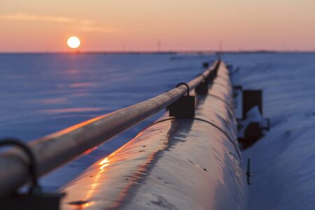 Gas pipelines, crane and pipes for gas and oil transportation, gas processing plant, against the backdrop of sunsetの写真素材
