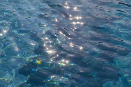 texture, background water surface in a pool with reflection of sunlight, blue bottom of a pool of waterの写真素材
