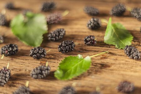 Fresh black mulberry with leaves on the wooden background, selective focusの写真素材