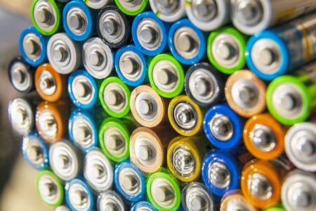 Energy abstract background of colorful batteries.Close-up group of alkaline battery top view. Several batteries in rows, on a mirror surfaceの写真素材