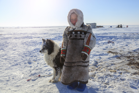 Nadym, Russia - april 27, 2018: tundra, open area, the boy with a dog in cold winter weather, the boy  in national clothes,のeditorial素材