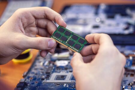 the concept of computer hardware, mobile phone, electronic, repairing, upgrade and technology. Repairman changes memory card in laptopの写真素材