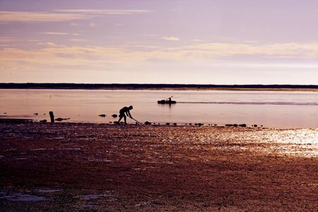 View of man working on sand and other man riding a sports boat.の写真素材