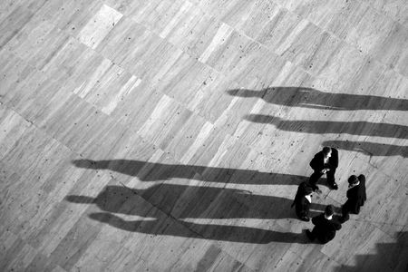Group of business men gathered on a circle with long shadows.の写真素材