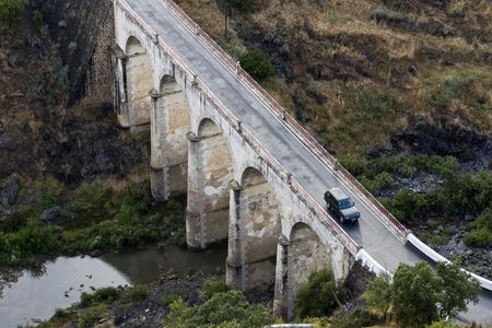 Top view of a arc stoned bridge over a river with a car passing by.の写真素材
